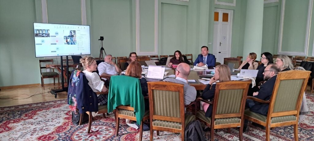 Group of people sitting aorund a round table with computers out