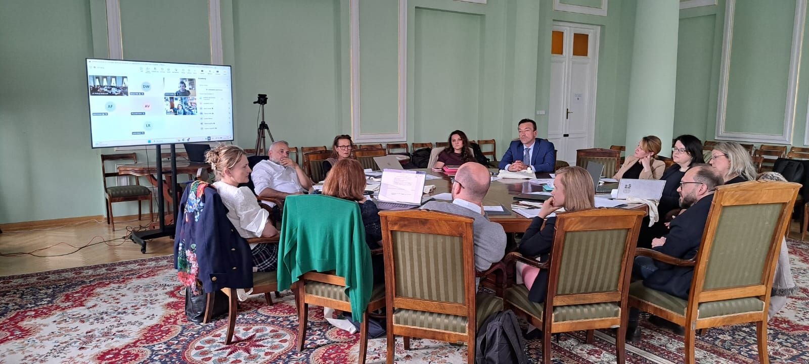 Group of people sitting aorund a round table with computers out
