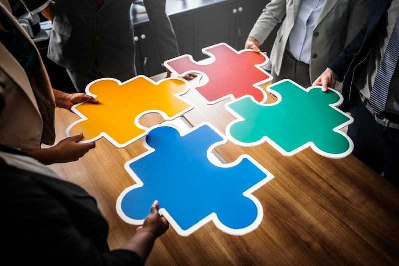 Business people connecting large puzzle pieces on a table