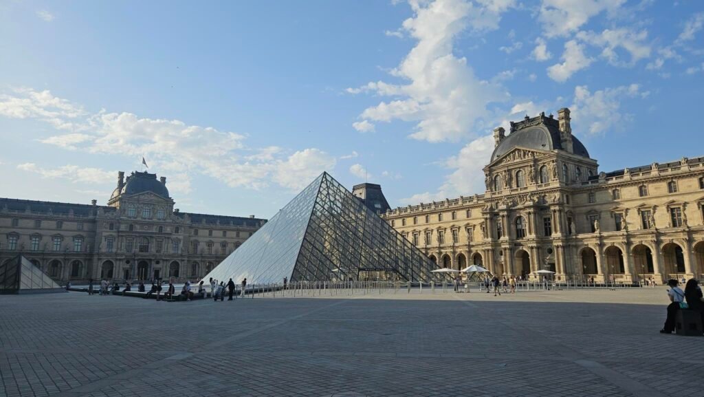Photograph of the Louvre Museum showing the Glass Pyramid and part of the more traditional building behind it.