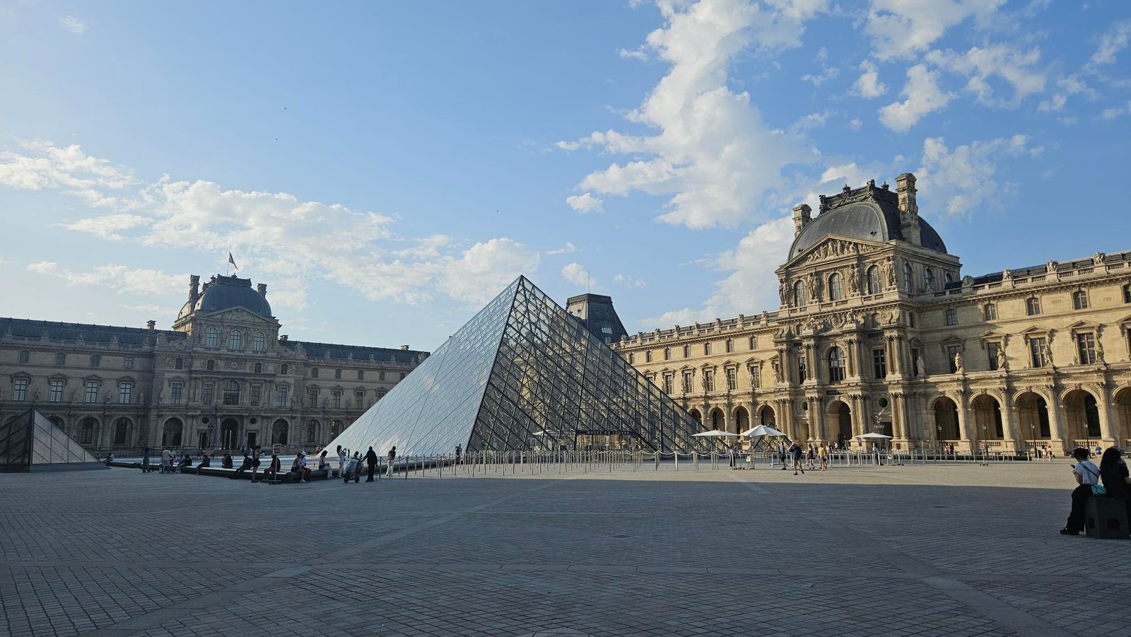 Photograph of the Louvre Museum showing the Glass Pyramid and part of the more traditional building behind it.